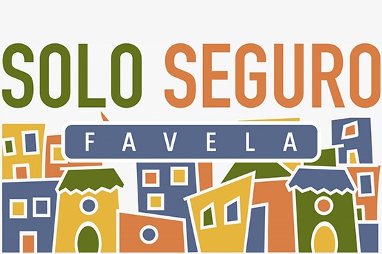 A imagem contém um desenho estilizado de uma favela com várias casas coloridas em tons de laranja, azul, verde e amarelo. No topo da imagem, há o texto "SOLO SEGURO" em letras grandes, com "SOLO" em verde e "SEGURO" em laranja. Abaixo desse texto, há uma faixa azul com a palavra "FAVELA" escrita em branco. As casas têm formas e tamanhos variados, com janelas e portas desenhadas de maneira simplificada.